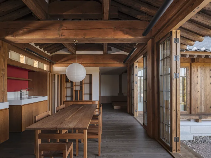 Open-plan interior showing timber framing, dining area, and sliding paper screen doors to courtyard