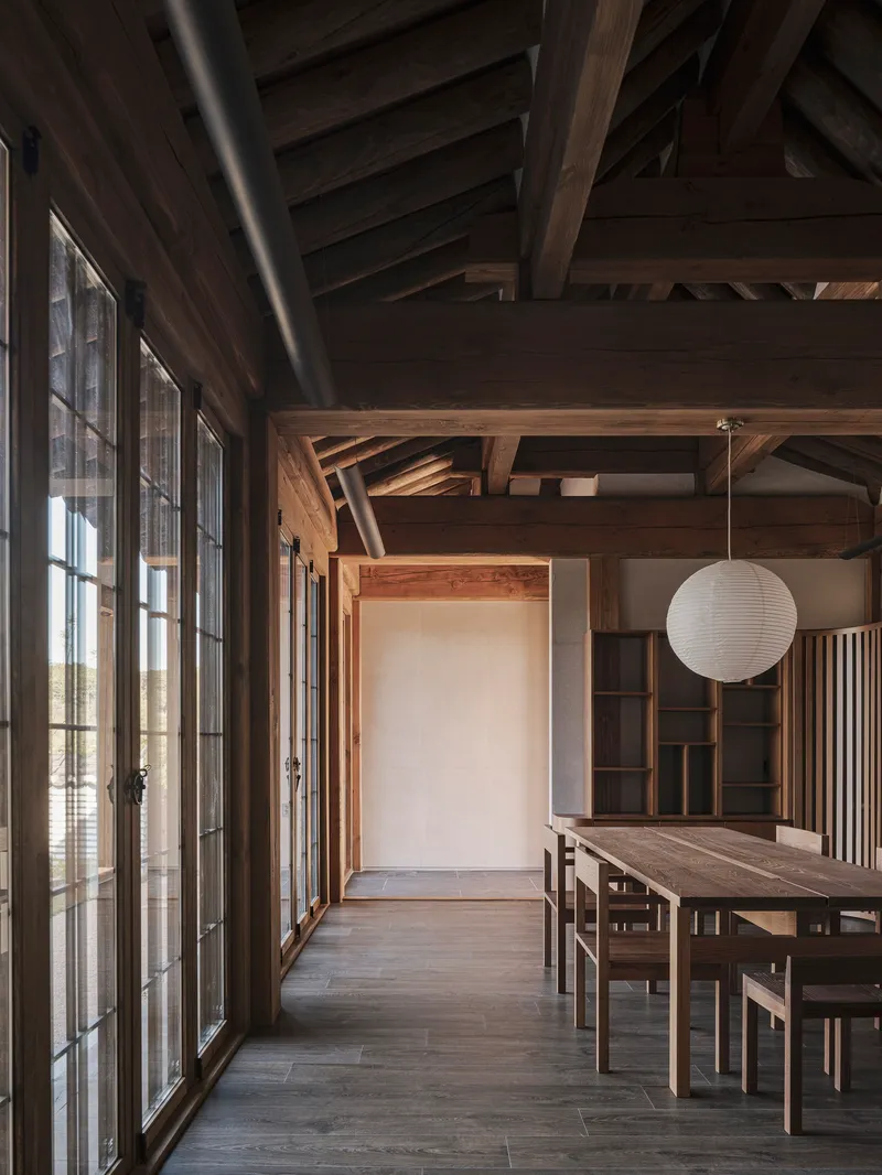 Dining area with exposed timber framing and a paper globe pendant above the table