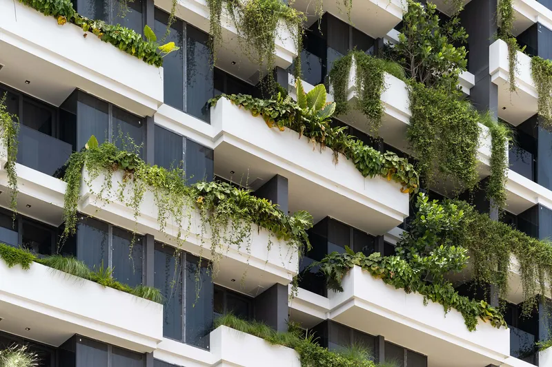 Stacked balconies with trailing vines and potted plants cascading over white concrete edges