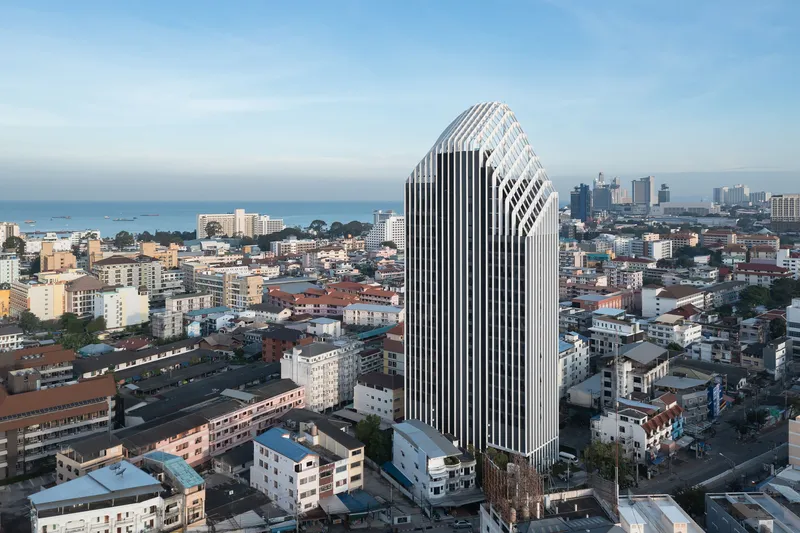 Aerial view of the white vertical fin facade rising above the surrounding residential neighborhood at dusk
