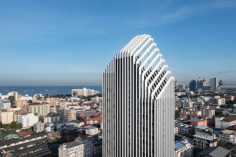 The tower's diamond-topped profile with alternating dark and light vertical louvers against the coastal skyline