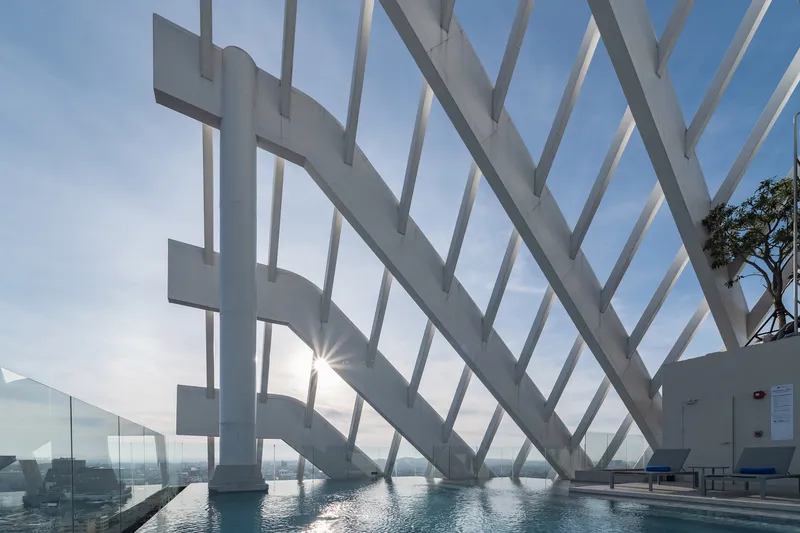 White diagonal structural ribs forming a sheltered terrace with a reflecting pool at sunrise