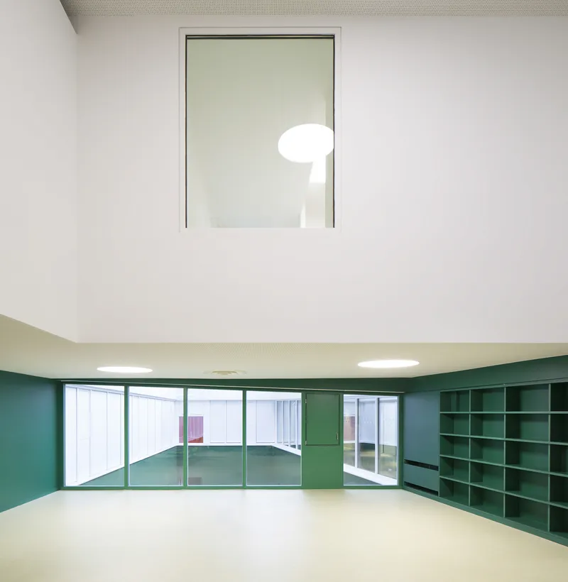 Curved classroom interior with green built-in shelving and a high window framing an illuminated sphere