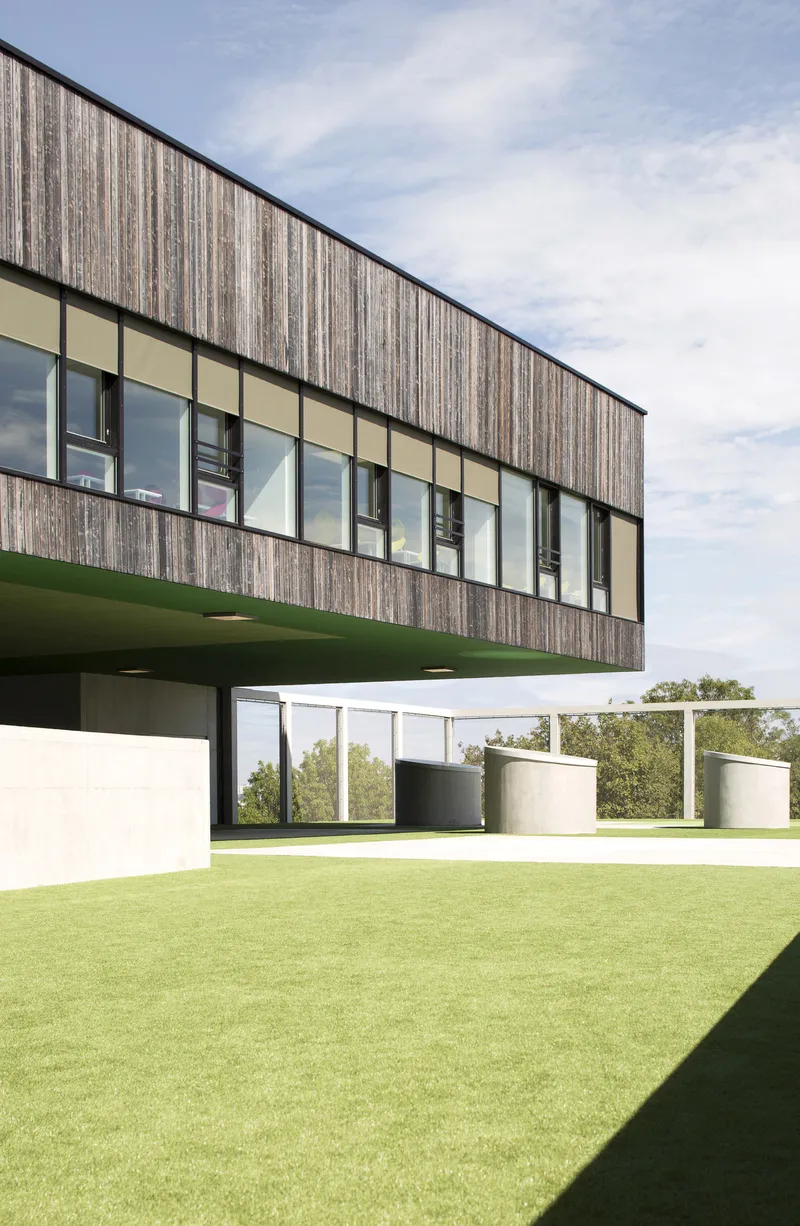 Cantilevered upper volume with vertical timber cladding and ribbon windows over green lawn
