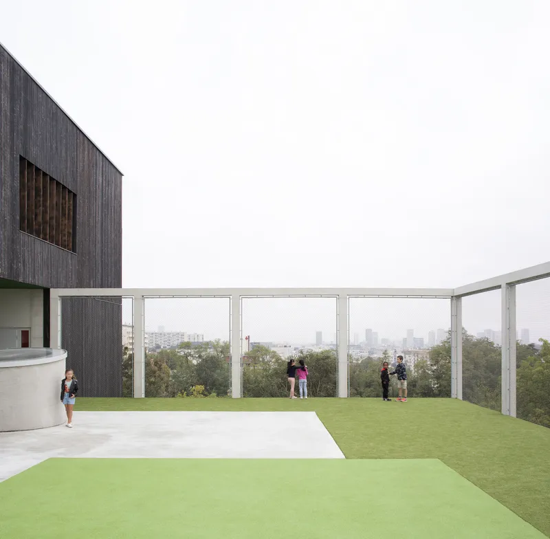 Rooftop terrace with white metal railing and visitors overlooking a distant cityscape in hazy light