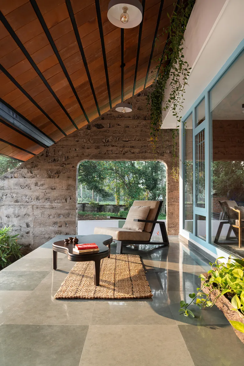 Covered terrace with boardformed concrete walls and arched opening framing garden beyond