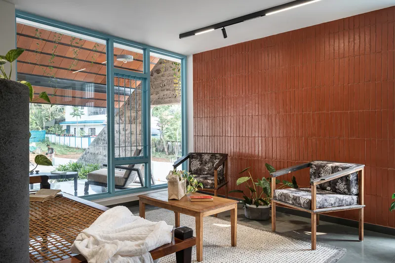 Living room with terracotta tile wall and blue metal framed doors opening to a courtyard