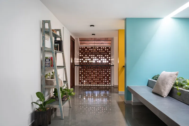 Hallway view toward a perforated screen wall filtering daylight into the polished concrete floor
