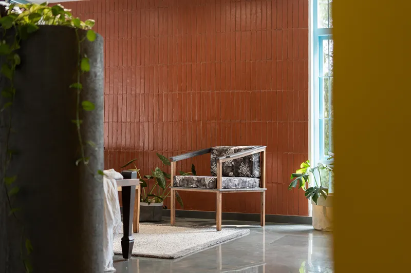 Seating area against terracotta tile wall with potted plants and blue window frame at edge