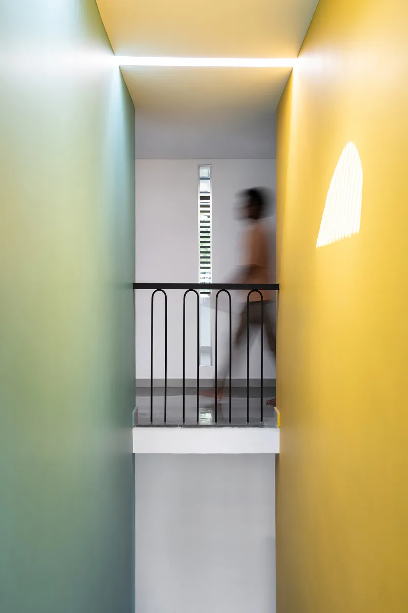 Stairwell with black metal railing framed by yellow and green painted walls and skylight above