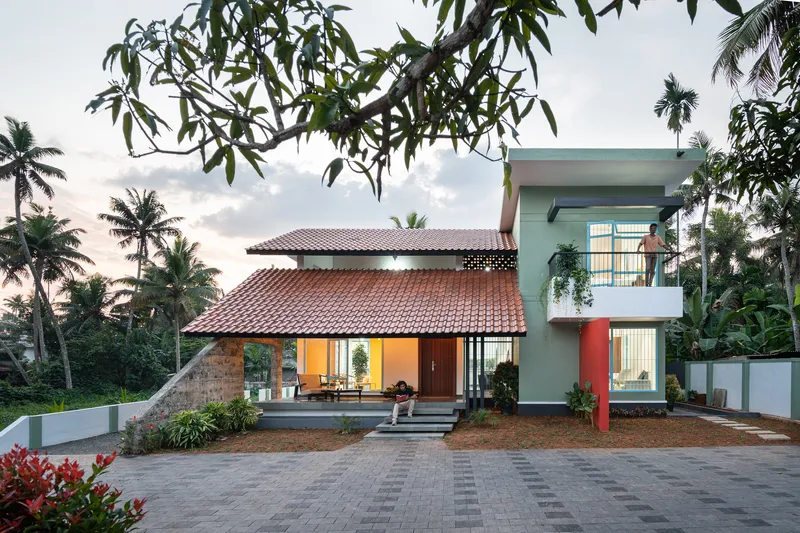 Street view of the residence with terracotta tile roofs and palm trees under an overcast sky