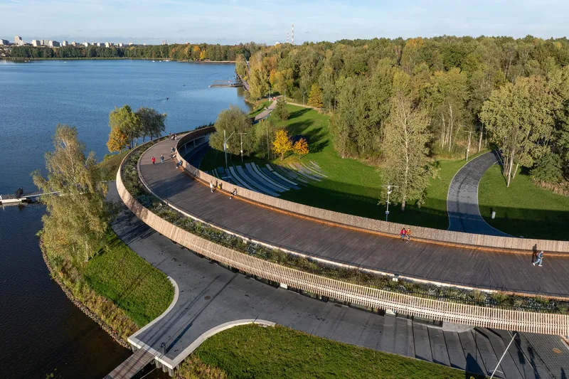 Aerial view of the curved boardwalk and amphitheater terraces along the lakefront with cyclists passing