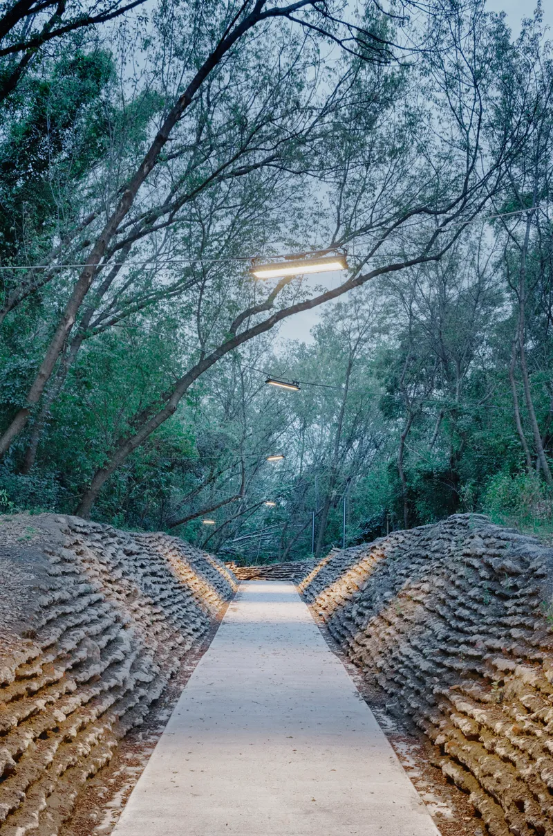 Stone wall passage illuminated at dusk with bare tree branches overhead