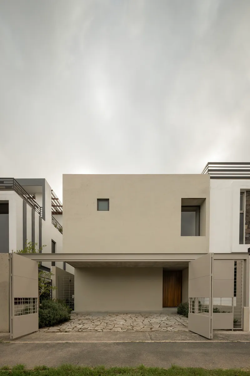 Street facade with recessed carport and cantilevered upper volume in smooth stucco under overcast sky