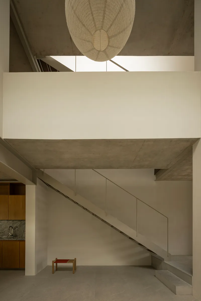 View across mezzanine bridge toward suspended paper lantern with staircase and kitchen below