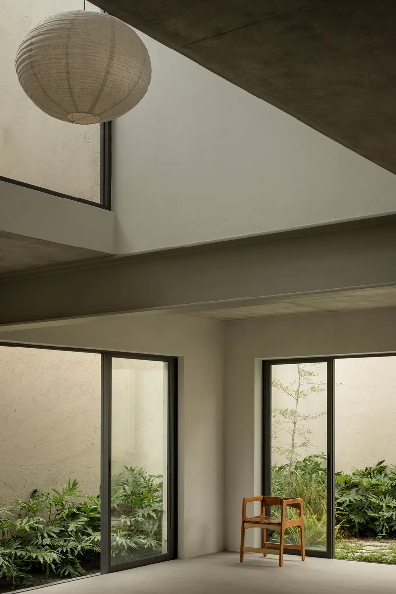 Double-height interior space with paper lantern and glazed doors opening to planted courtyards