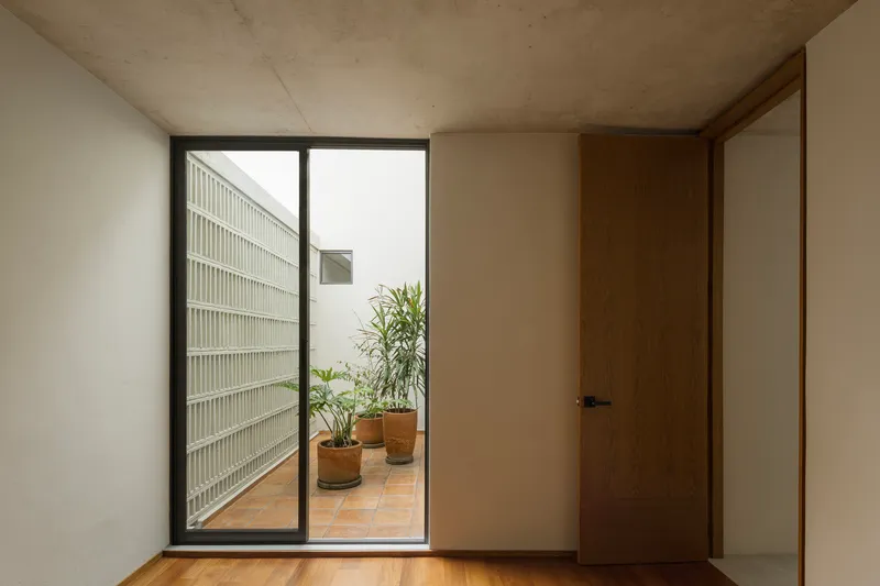 Interior room with timber door opening to tiled terrace and glass block wall