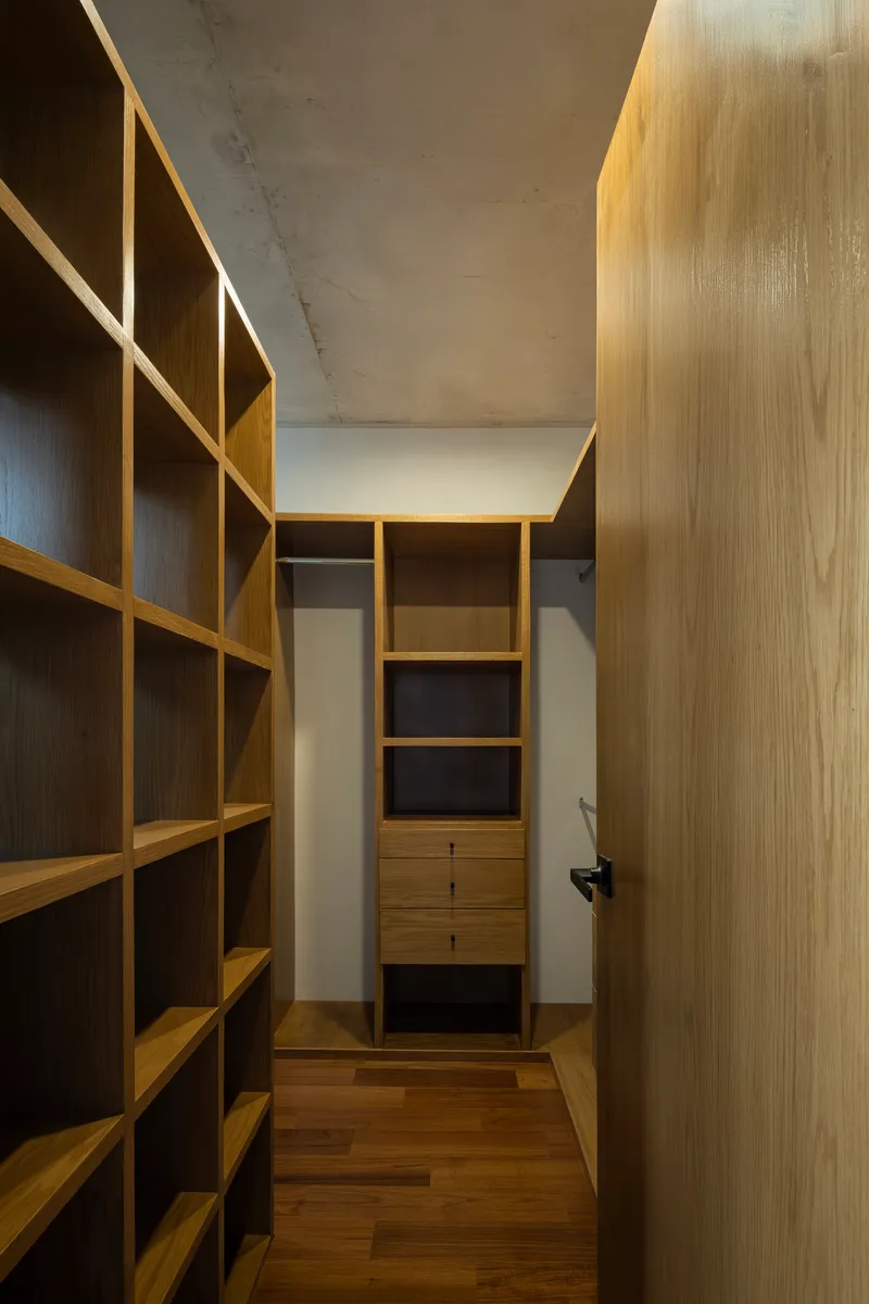 Timber storage corridor with exposed concrete ceiling and concealed lighting above shelving units