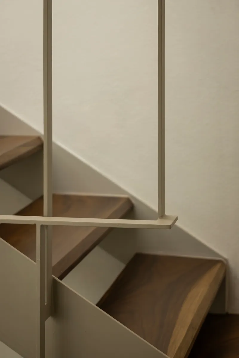 Close-up of timber staircase treads with metal balustrade casting afternoon shadow