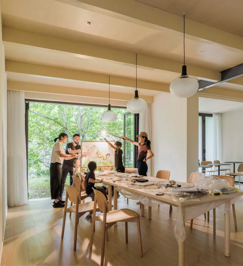 Reading room with timber table and pendant lights where a group gathers for an art workshop