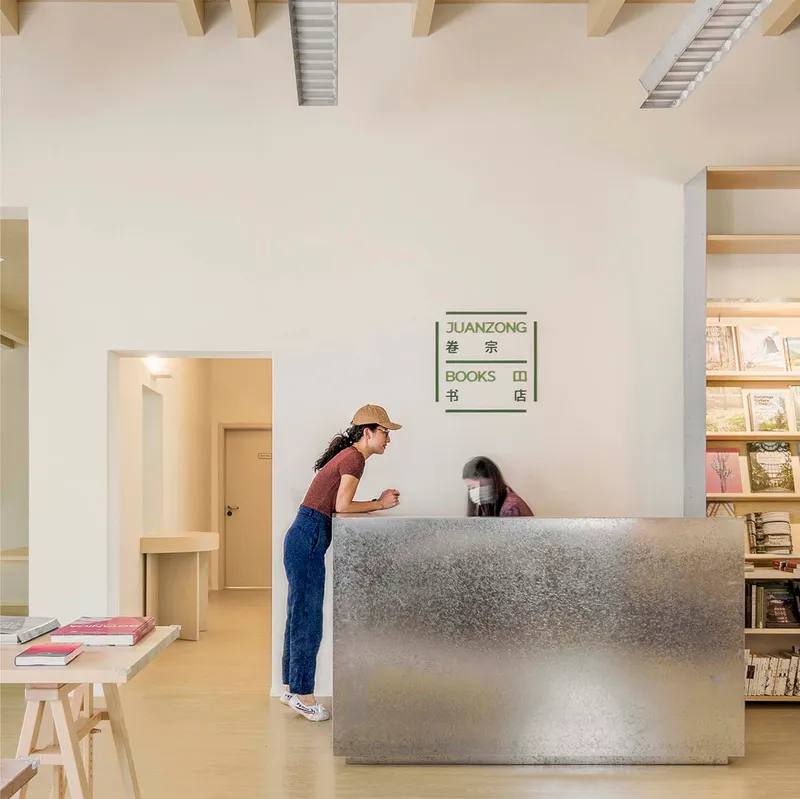 Textured concrete reception desk with a visitor in a straw hat standing at the counter