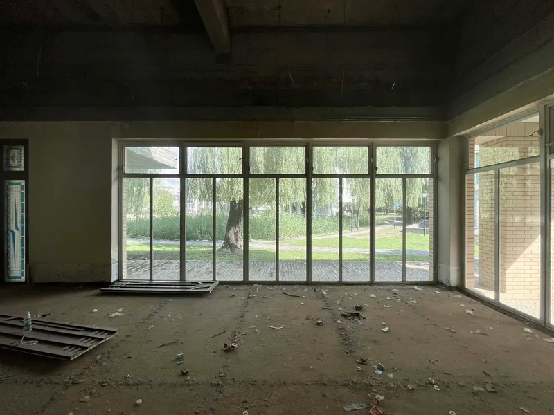 Unfinished room with floor-to-ceiling glazing overlooking willow trees and a paved courtyard