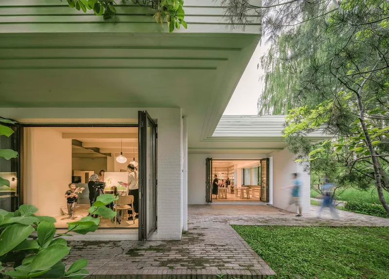 Covered walkway with exposed concrete ceiling beams and open folding doors leading to interior rooms
