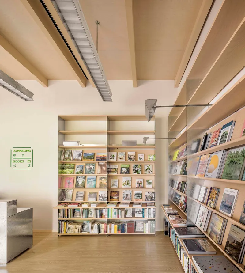 Interior library space with floor-to-ceiling shelving displaying books and exposed wooden ceiling beams