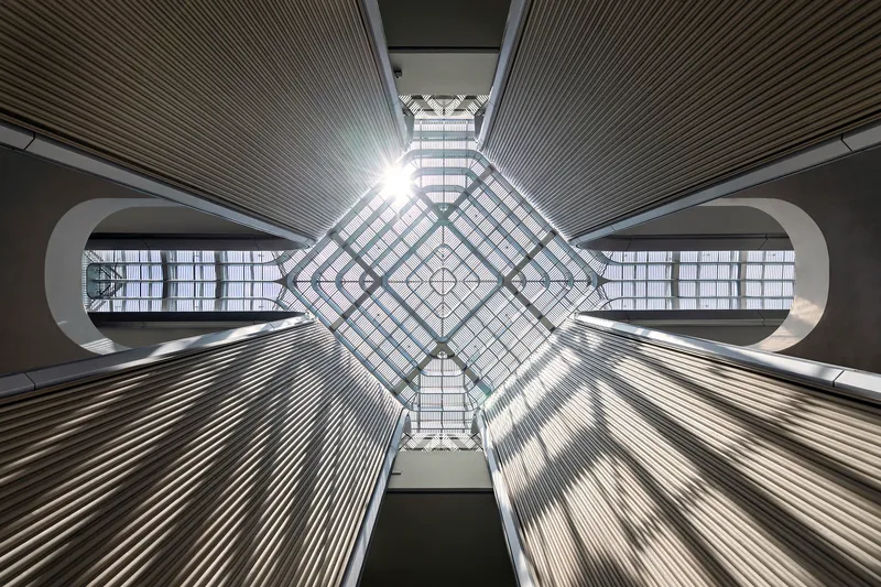 View directly upward into the diamond-grid skylight with radiating ribbed ceiling panels and bridge openings