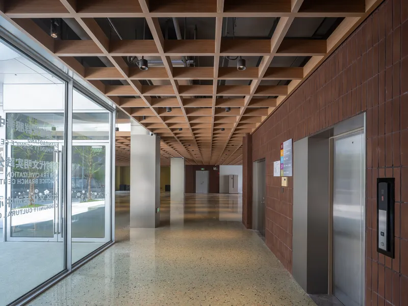 Entrance hall with timber coffered ceiling and brown tiled wall flanking the elevator bank