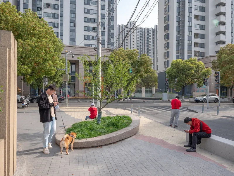 Curved concrete planter with shrubs in a street plaza where residents walk dogs and gather