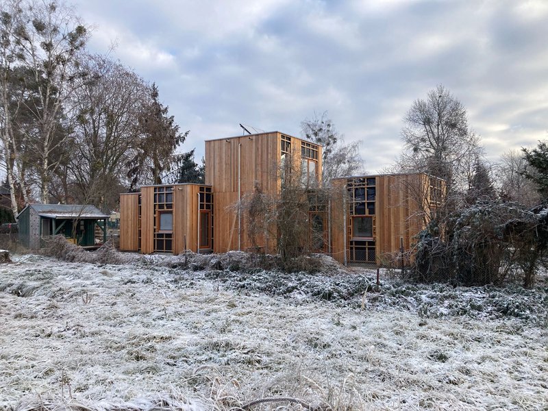 Clustered timber volumes with varied cladding tones set in a snow-dusted landscape under overcast winter sky