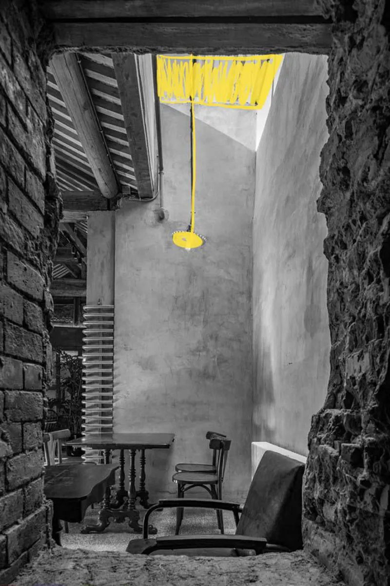 A quiet seating corner framed by raw brick, concrete walls, and a highlighted suspended light installation.