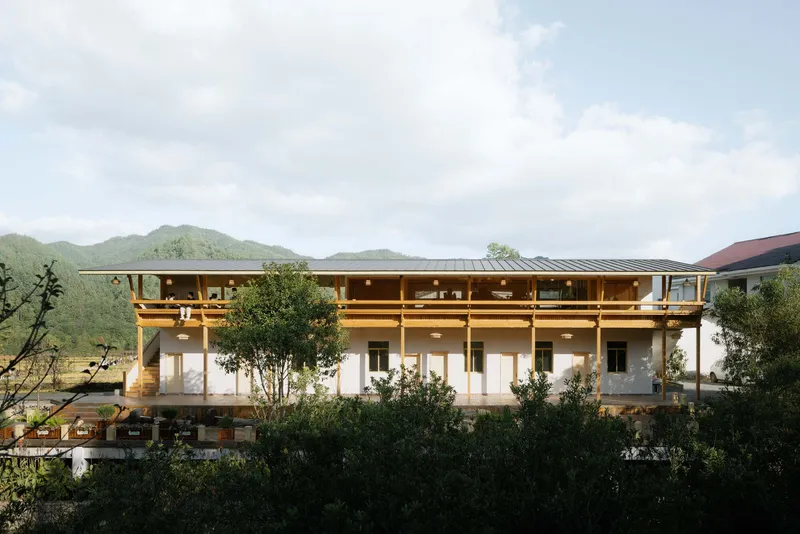 Three-story facade with exposed timber frame and deep overhanging eaves set against forested mountains