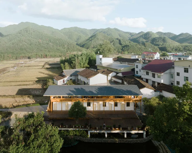 Aerial view of the white-rendered building with metal roof surrounded by rice fields and village houses