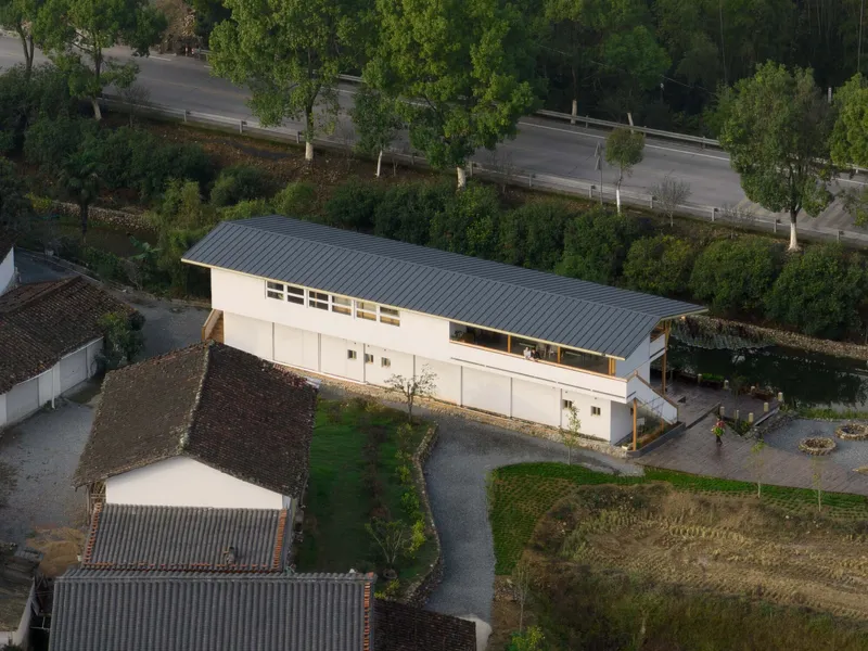 Aerial view showing the corrugated metal roof and clerestory windows adjacent to a tree-lined road