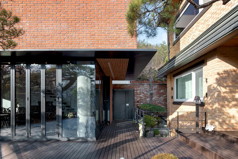 Timber deck terrace with glass doors under a brick overhang lined with slatted wood soffit