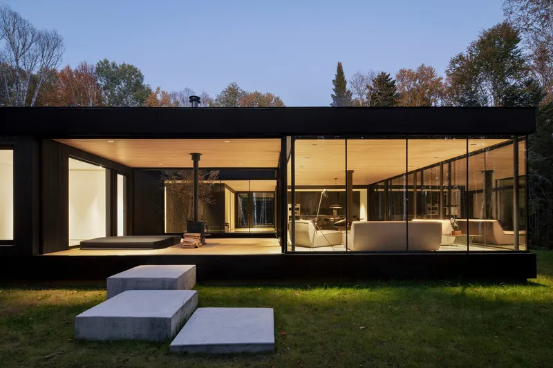 Fully glazed facade with timber soffit and concrete platform steps at dusk