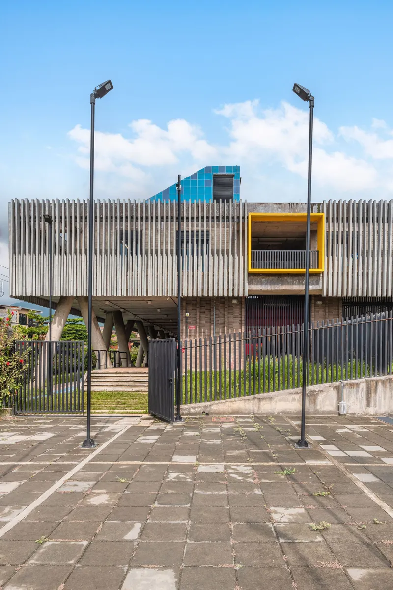 Street view of the vertical corrugated metal facade with yellow-framed openings beneath a cloudy sky