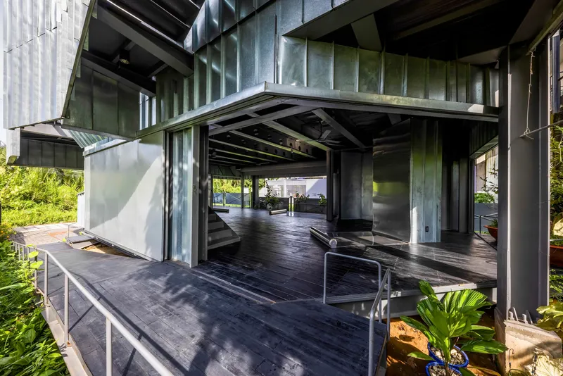 Covered terrace with operable metal panels, exposed concrete columns and timber decking
