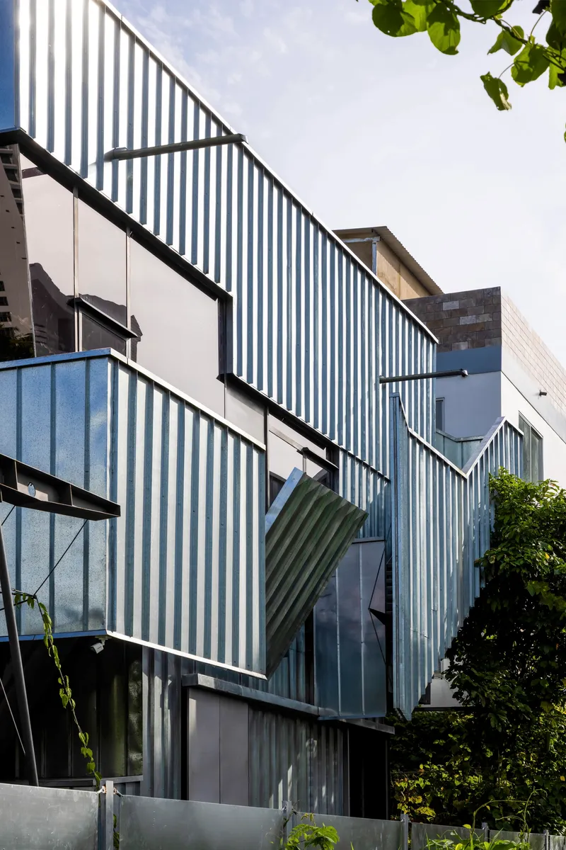 Detail of the articulated corrugated metal facade with angled panels and integrated window openings