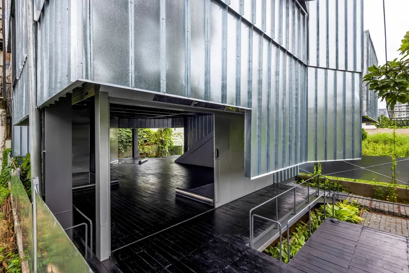 Elevated covered terrace with vertical metal cladding and black timber decking overlooking planted courtyards below