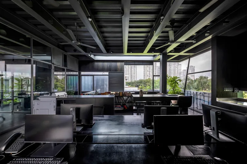 Office workspace with exposed steel ceiling structure and workstations arranged below continuous skylights