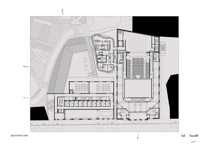 Ground floor plan drawing revealing large performance hall, seating rows, and circulation zones with adjacent courtyard