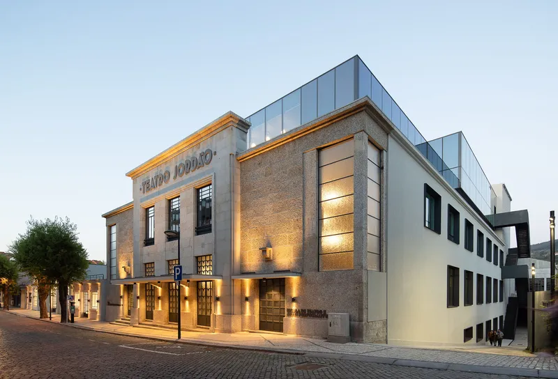 Street view of the stone and stucco facade with vertical glass addition rising above at twilight