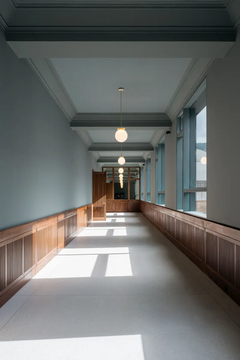 Timber-paneled hallway with cofferred ceiling and pendant lights in afternoon sunlight