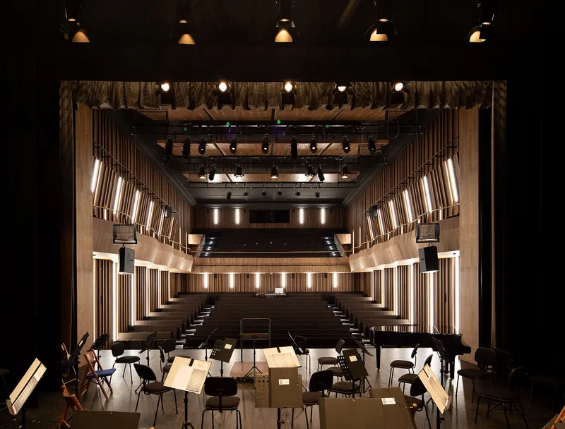 View from stage showing tiered timber seating, vertical illuminated panels and exposed ceiling rigging