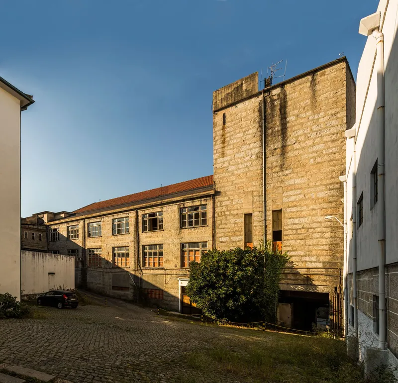 Courtyard view of weathered stone buildings with a tall tower and low wing at golden hour