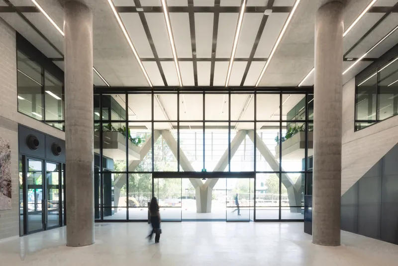 Lobby with concrete ceiling grid and glass walls overlooking the branching columns with a passing figure