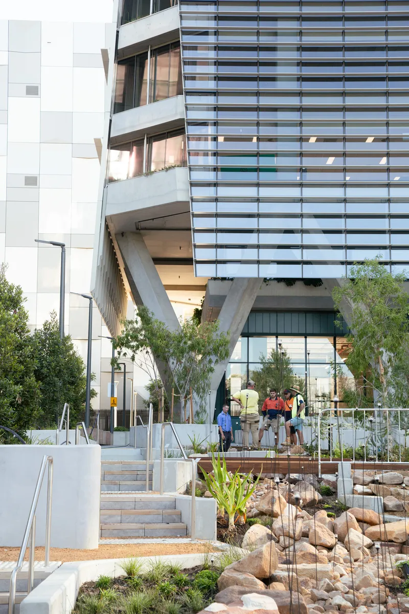 Landscaped entry plaza with stone terraces and native plantings beneath the cantilevered building volume